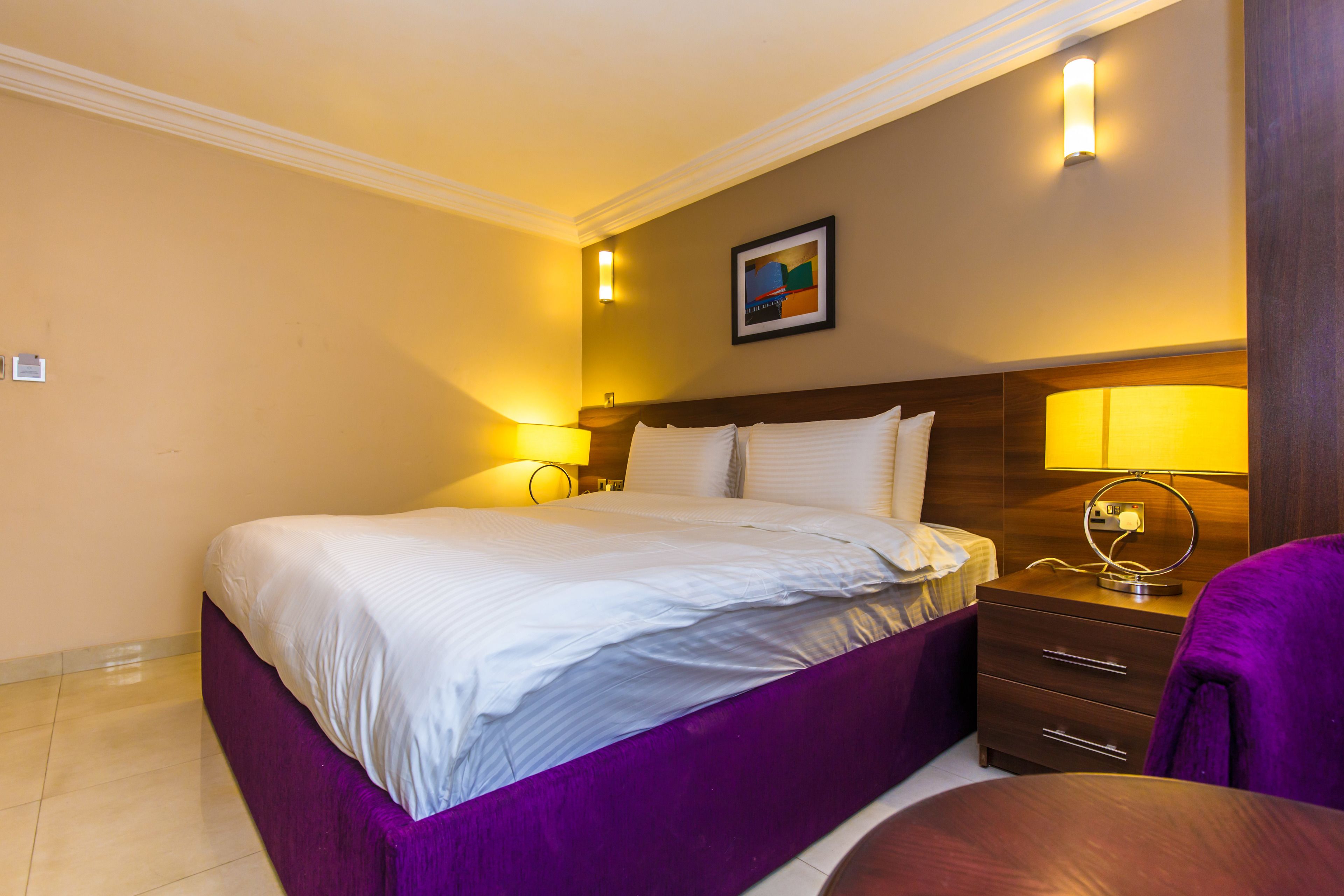 A hotel room with a large bed, two bedside tables with lamps, a small desk, and a chair.