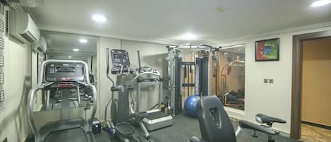 A home gym with treadmills, elliptical machines, a stationary bike, and a weight bench.
