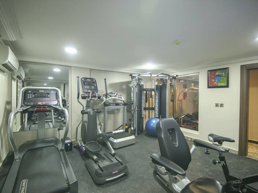 A home gym with treadmills, elliptical machines, a stationary bike, and a weight bench.