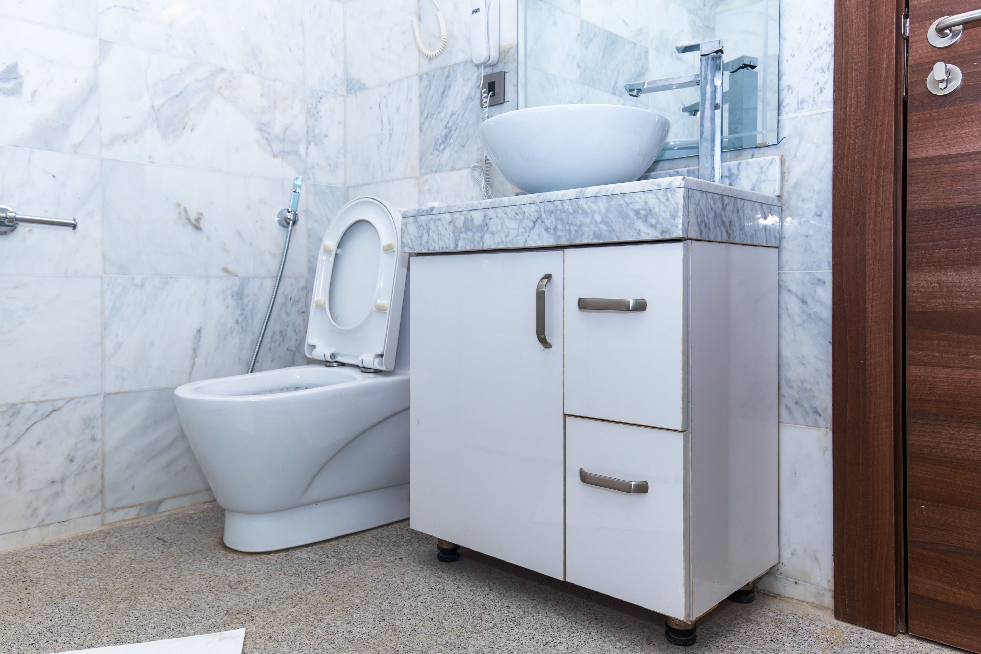 A bathroom with a toilet, bidet, and a cabinet with drawers.