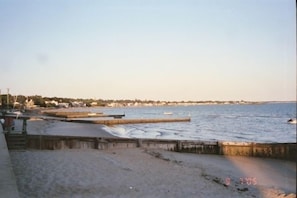 Een strand met een houten looppad, een zandstrand en een rustige zee.