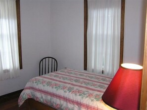 Une chambre à coucher avec un lit, une chaise et une lampe.