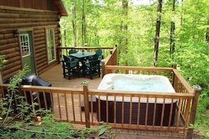 A wooden cabin with a deck, a hot tub, and a table with chairs. - Beautiful Log Cabin For Romantic Getaways 20 Acres (Logan)