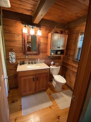 A wooden cabin bathroom with a double sink, toilet, and a mirror above the sink. - Beautiful Log Cabin For Romantic Getaways 20 Acres (Logan)