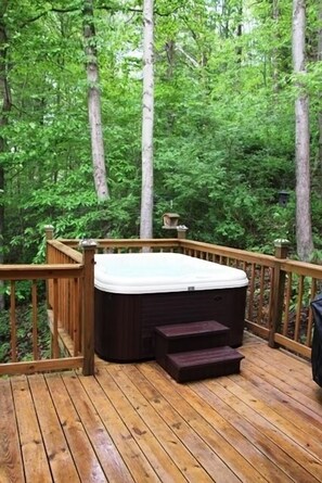 A hot tub on a wooden deck surrounded by dense forest. - Beautiful Log Cabin For Romantic Getaways 20 Acres (Logan)