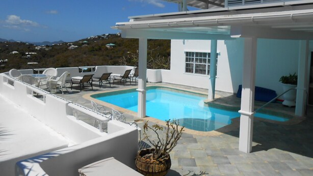 A modern outdoor pool area with white walls and a clear view of the surrounding landscape.