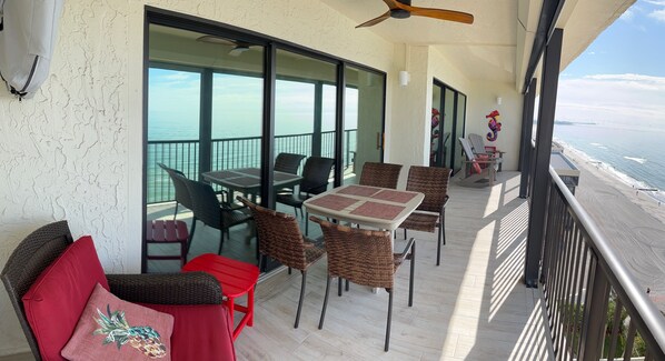 Ein Balkon mit Korbmöbeln, einem roten Stuhl und einem Tisch.