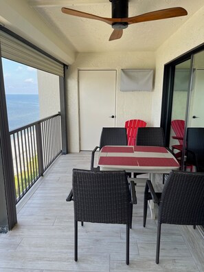 Ein Balkon mit Tisch und Stühlen, einem Deckenventilator und Blick auf das Meer.