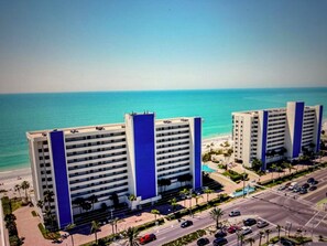 Ein hoch aufragendes Hotel mit zahlreichen Stockwerken, einem auffälligen, blauen, vertikalen Streifen und Blick auf Strand und Meer.