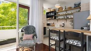 A modern kitchen with a large window, wooden flooring, and a dining area with chairs. - St Martini 416 (Cape Town)