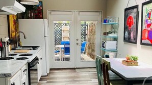 Een keuken met witte kasten, een fornuis en een eethoek met een tafel en stoelen.