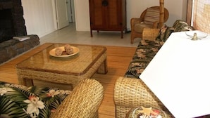 Ein Wohnzimmer mit einer Couch, einem Couchtisch, einem Korbstuhl und einem Holzschrank.
