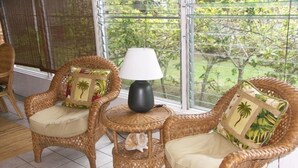 Ein Zimmer mit Korbmöbeln, darunter zwei Stühle und ein kleiner Tisch mit einer Lampe.