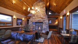 A cozy interior with a stone fireplace, leather furniture, and wooden beams. - Luxury Big Sky Mountain Home With Private Lodge, Pool & Ski in/out access (Big Sky)