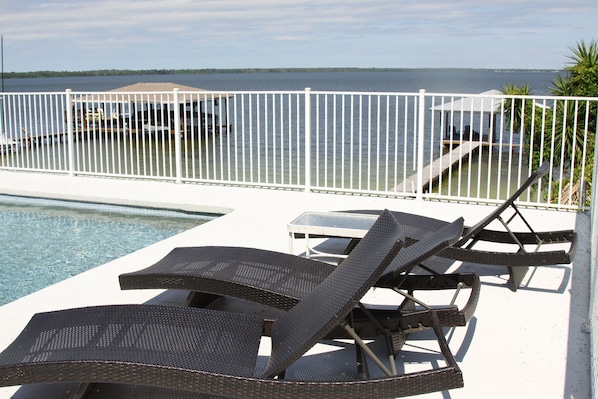 A poolside area with lounge chairs and a view of the water.