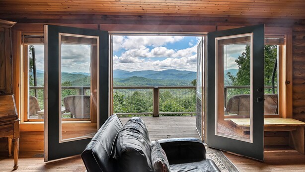 Una habitación con techo de madera, un ventanal grande y vistas a montañas.