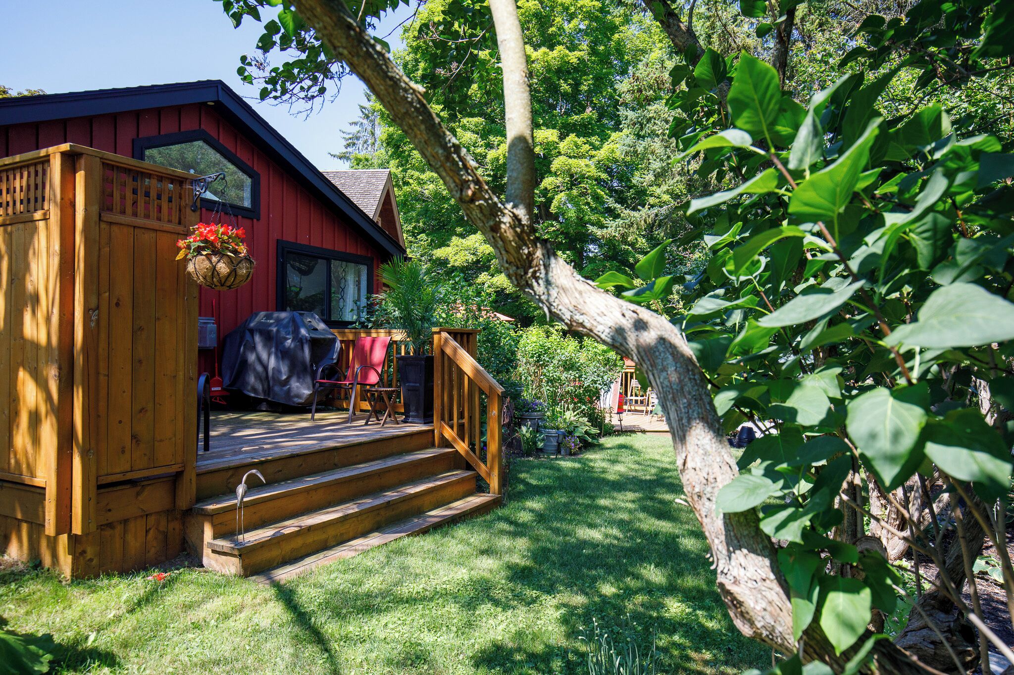 A wooden cabin with a porch, steps, and a hanging flower basket.