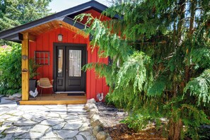 A red building with a black door, a wooden porch, and a stone pathway leading to the entrance. - Runaway Rooster B&B -- Guest Cottage
 (Prince Edward)