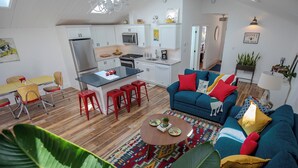 Un espacio habitable compacto con kitchenette, comedor y zona de estar con sofá y sillones.