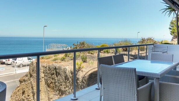 A balcony with a table and chairs overlooking the sea. - Dunmore Place (Cape Town)
