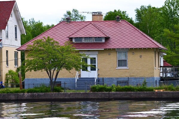 A two-story house with a red roof, a white door, and a small porch.