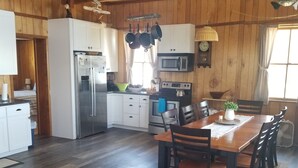 Una cocina amplia con pisos de madera, un comedor con mesa y sillas de madera, y un gran ventanal que proporciona luz natural.