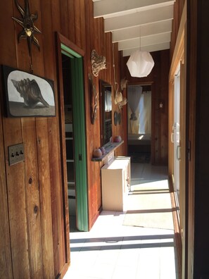 Enter a cozy hallway with a wooden door, decorative shelf, and starfish wall decoration.
