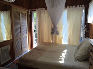 Cozy retreat with a large bed, white quilt, and a window with white curtains.