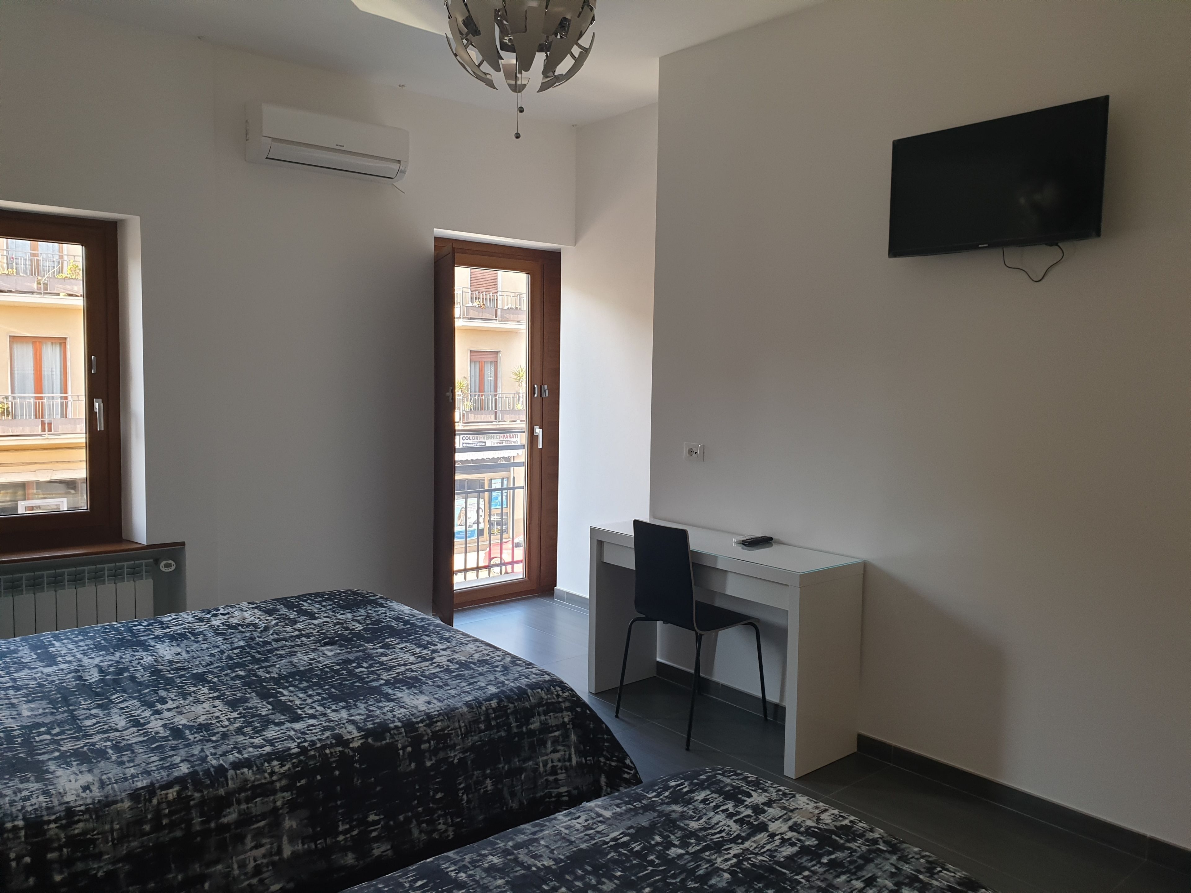 A bedroom with two beds, a desk, and a TV.