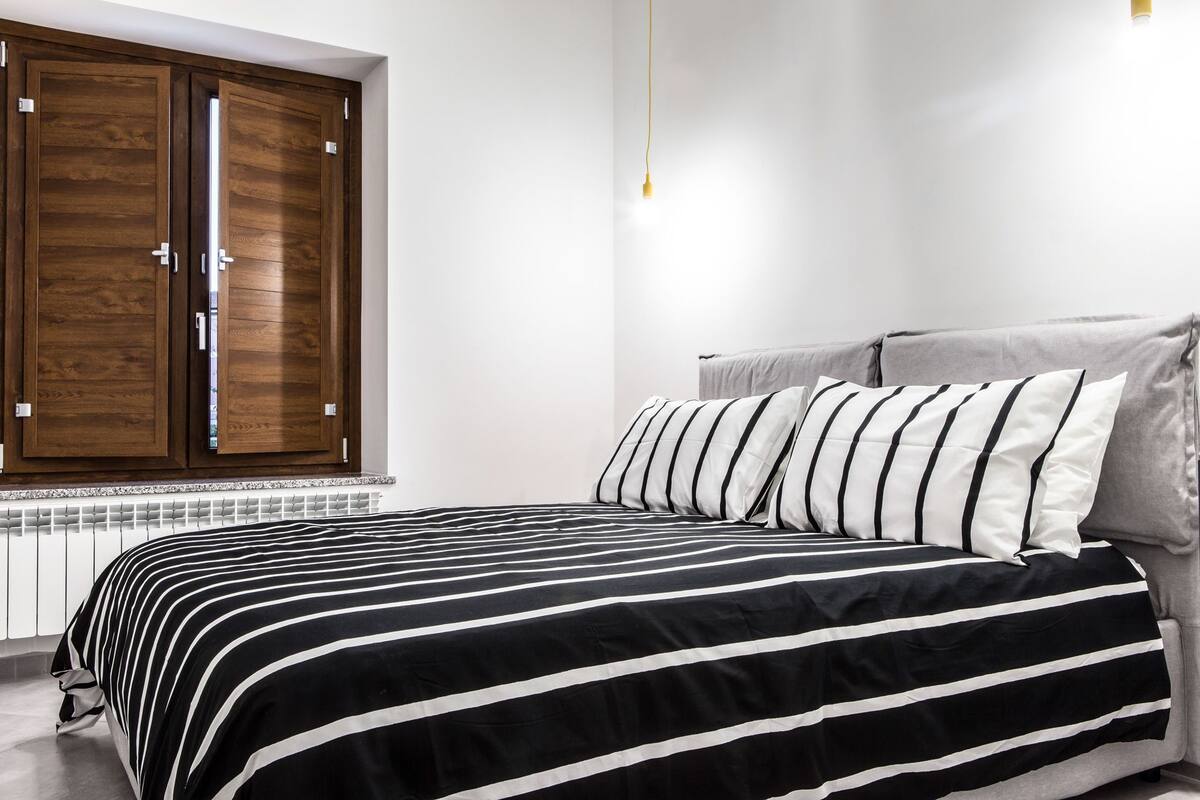 Une chambre à coucher avec un lit, une fenêtre avec des volets en bois et un radiateur.
