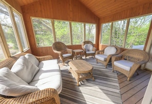 A wooden deck with wicker furniture, including a sofa and chairs, and large windows offering a view of trees. - Cozy cul de sac location on the northern quarter of the Galena Territory (Galena)