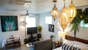 Una habitación luminosa con cama, sofá, mesa de comedor y televisor.