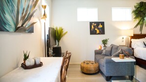 Una habitación de hotel moderna con cama, sofá, mesa de centro y ventilador de techo.