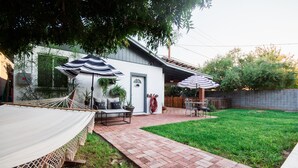 Un patio trasero con una hamaca, muebles de jardín y sombrillas.