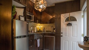 Una cocina con armarios de madera oscura, electrodomésticos de acero inoxidable, un salpicadero decorado y una puerta blanca con un cartel de bienvenida.