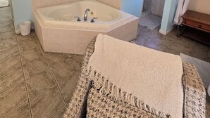 A bathroom with a bathtub, a towel rack, and a painting on the wall.