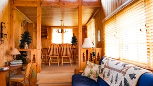 L’intérieur chaleureux d’un chalet comprend un coin repas, un canapé recouvert d’une courtepointe et des murs en bois.