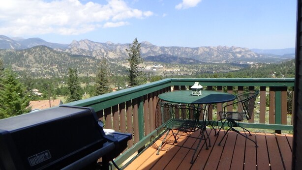 Une terrasse dotée d’un barbecue, d’une table et de chaises, offrant une vue sur un paysage montagneux.