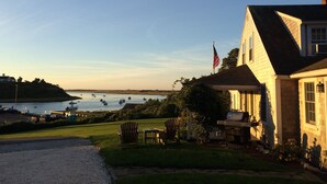 Ein Haus mit Veranda, einer Flagge und Blick auf Boote auf dem Wasser.