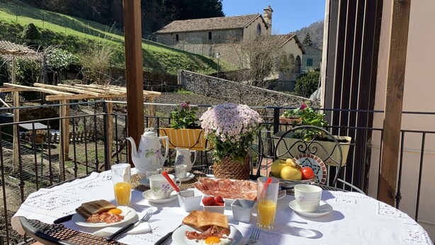 Ein Esstisch, gedeckt für ein Frühstück, mit schöner Aussicht auf einen Hügel und ein Gebäude im Hintergrund.