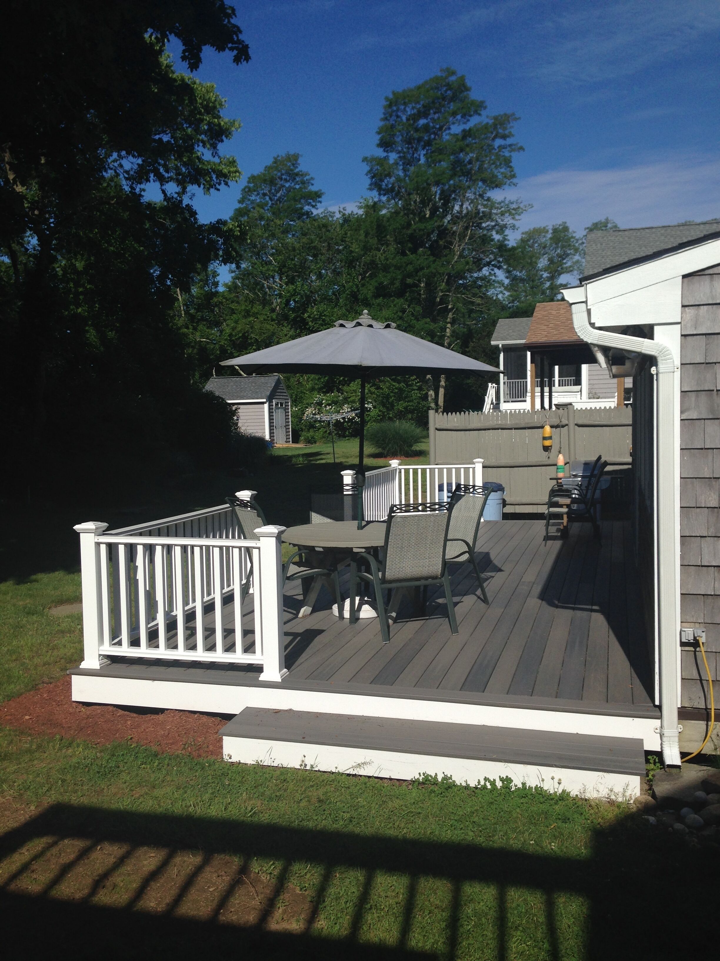 A deck with a table and chairs, a pergola, and a white railing.