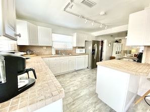 A modern kitchen with white cabinetry, a stainless steel refrigerator, and a microwave.