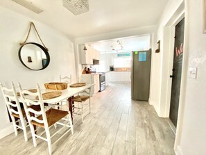 A spacious kitchen with white cabinetry, a dining table with chairs, and a large mirror on the wall.