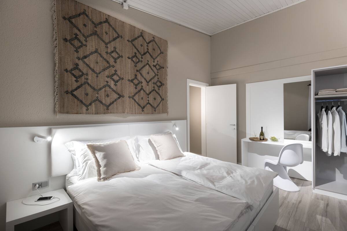 Un dormitorio moderno con una cama grande, mesitas de noche, un armario y un adorno en la pared.