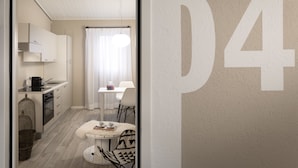 A modern kitchen with white cabinets, a dining area with a table and chairs, and a large number '04' on the wall. - CP Resort (Torricella Taverne)