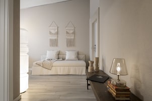 Quarto com cama, mesa de cabeceira, luminária e decoração na parede.