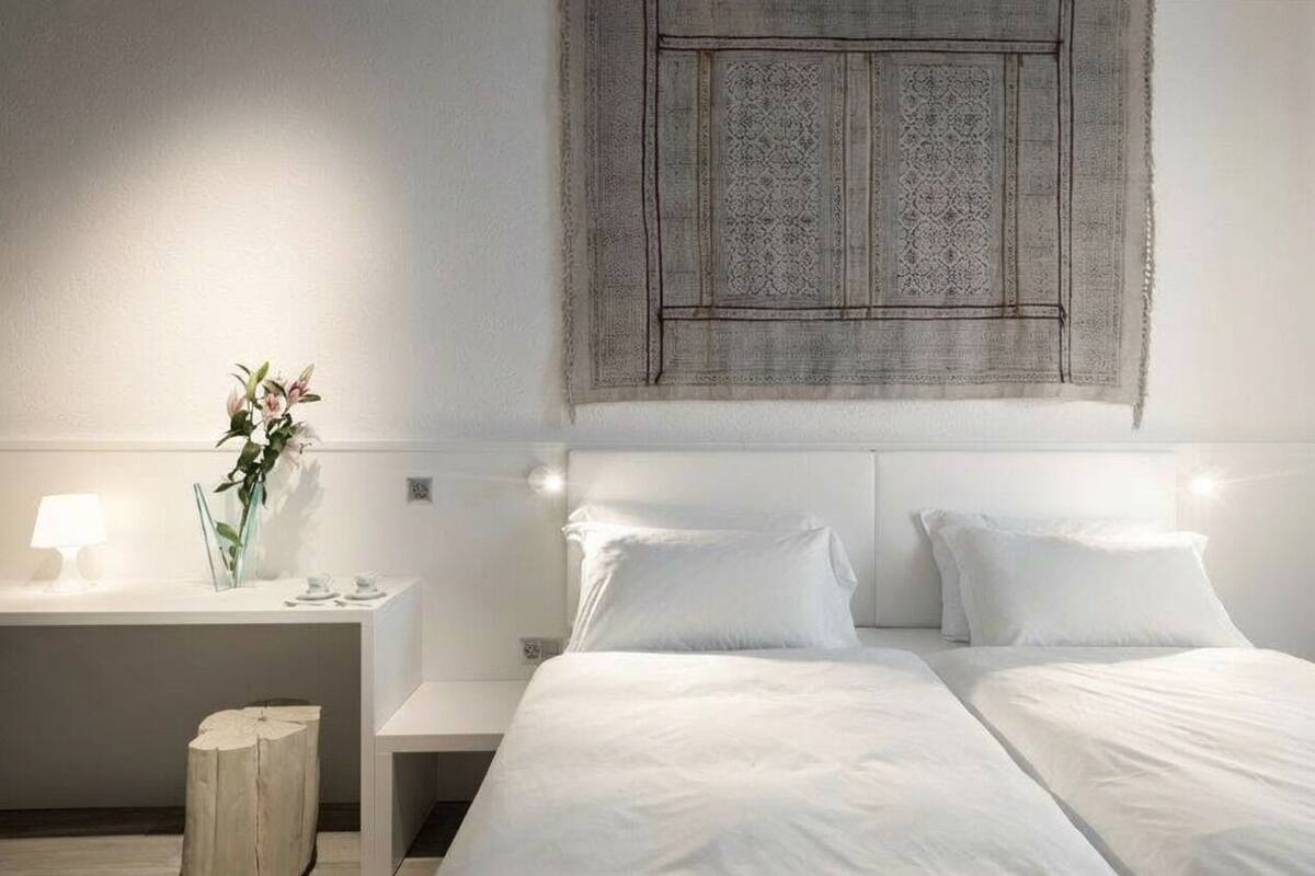 Una habitación de hotel moderna con una cama grande, mesitas de noche y un cuadro decorativo en la pared.