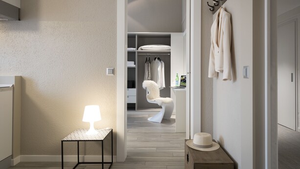 A hallway with a white lamp, a mirror, and a hat on a small table. There is a closet with clothes and a white chair in the background. - CP Resort (Torricella Taverne)