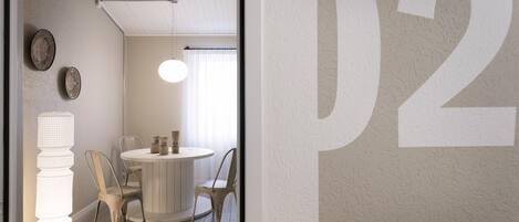 A room with a round table, two chairs, a tall floor lamp, and a wall with a large 'P2' sign.
