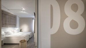 A modern bedroom with a large bed, a bedside table, and a wall-mounted light fixture. - CP Resort (Torricella Taverne)